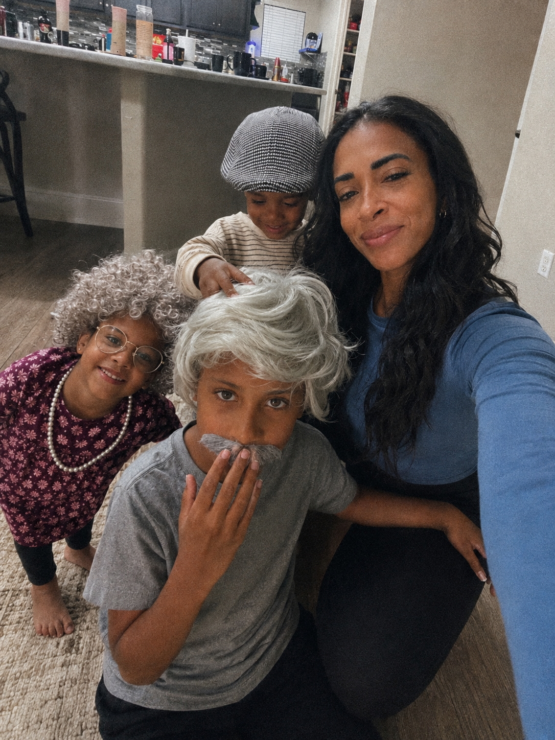Heather Everett taking a selfie with her three children in fun 100th-day-of-school costumes