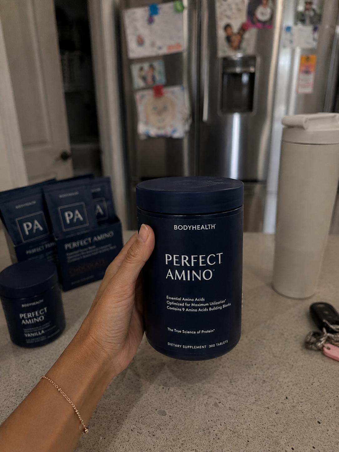 BodyHealth Perfect Amino supplement held in hand on kitchen counter